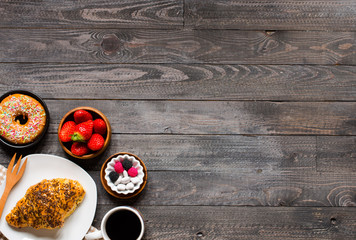 Coffee and croissant for breakfast, on rustic wooden background,