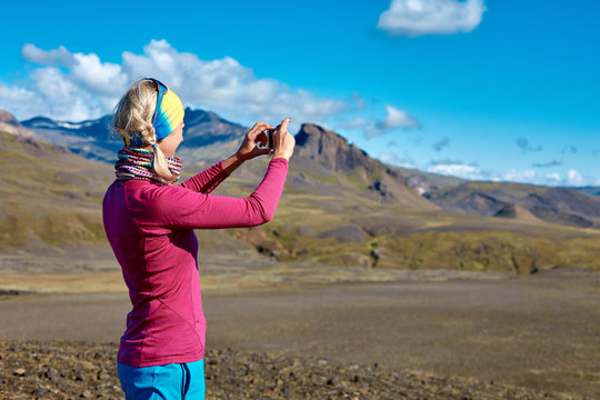 woman hiker photographer taking picture on the mountain background in Iceland