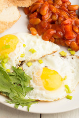 Fototapeta na wymiar Fried eggs, beans in tomato sauce on a white plate close-up.