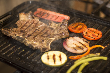 Grilled beef steak with sausage, mixed grilled vegetables. 