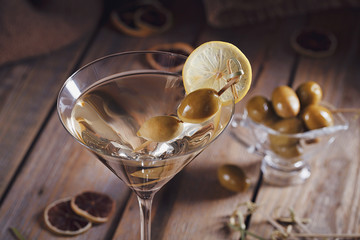 Glass of martini with green olives on a old wooden table