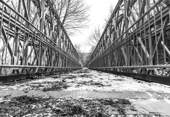 Symmetrical metal bridge with footpath from low perspective with wide angle, high contrast balance in black and white