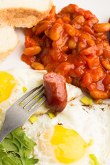 Fried eggs, beans, sausages and bread close-up.