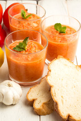 Tomato soup gazpacho, bread and vegetables on a white background.