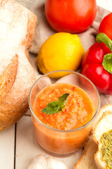 Gazpacho, bread, pesto and vegetables closeup on a wooden background.