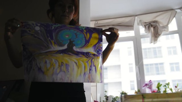 Making painting in Liquid Ebru art technics Process of painting - woman shows created colorful picture