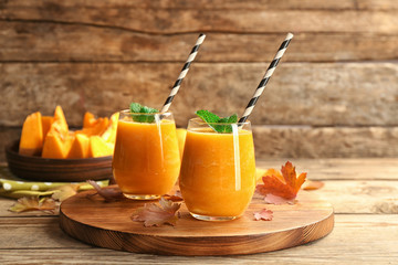 Two glasses with pumpkin smoothie on wooden board