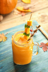 Jar with pumpkin smoothie on wooden background