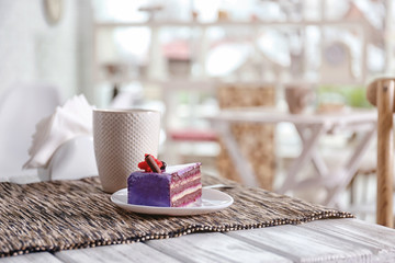 Plate with tasty cake and cup of tea on table in cafe