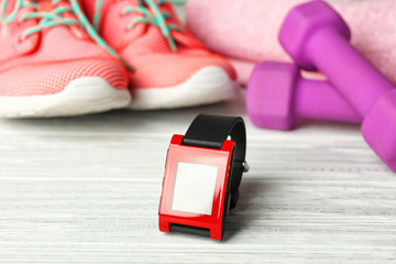 Heart rate monitor watch and sportive equipment on light wooden background