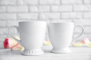 Cups and flower on white brick wall background