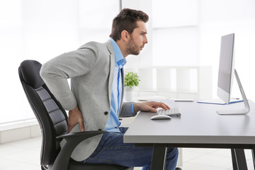 Incorrect posture concept. Man sitting at office table