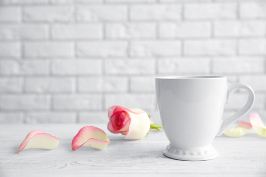 Cup and flower on white brick wall background