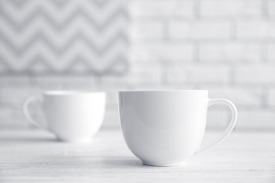 Blank ceramic cups on white table