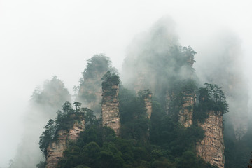 mountains are surrounded by clouds at Zhangjiajie, a national park in China known for its surreal...