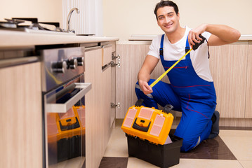 Young repairman working at the kitchen