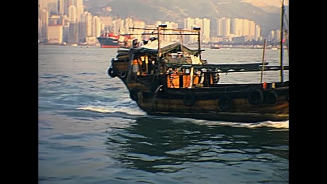 airplane taking off in Hong Kong skyline, Victoria Harbour with Sampan fishing boat. Historic restored archival footage on 1980s.