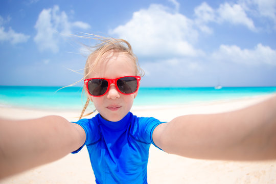 Adorable little girl making selfie at tropical white beach