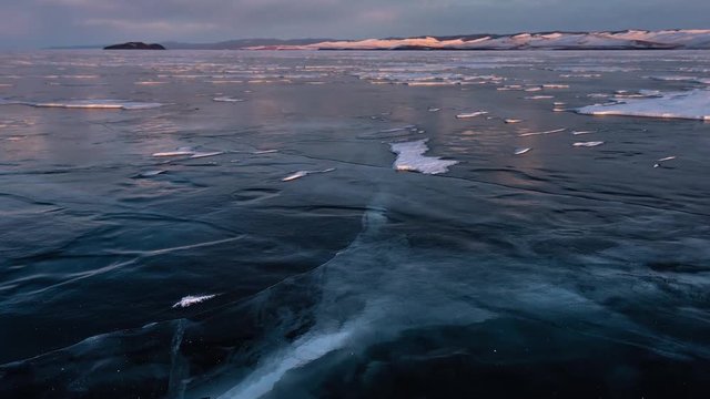 Time Lapse. The surface of the ice on the frozen lake in the rays of the setting sun. Baikal, Russia.