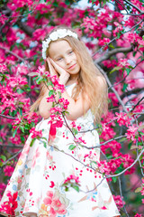 Fototapeta premium Adorable little girl in in blooming apple tree garden on spring day