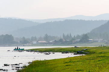 fishermen standing in the water near board and old russian village