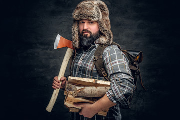 Portrait of brutal bearded hunter male holds an axe on his shoulder.
