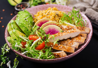 Healthy salad with chicken, tomatoes,  avocado, lettuce, watermelon radish and lentil on dark background.