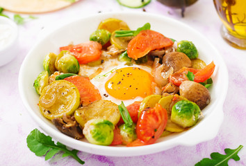 Fried eggs with vegetables - shakshuka and fresh cucumber, watermelon radish and arugula