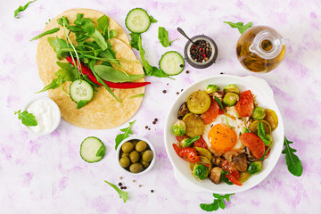 Fried eggs with vegetables - shakshuka and fresh cucumber, watermelon radish and arugula. Flat lay. Top view