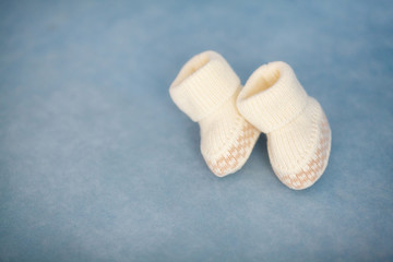 White crochet baby booties on blue background, closeup