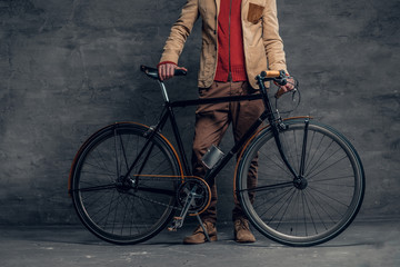 A man posing with single speed bicycle over grey background.