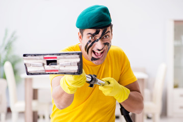 Funny man in military style cleaning the house