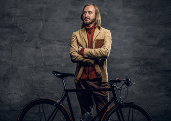 Obraz na płótnie Canvas A man posing with single speed bicycle over grey background.
