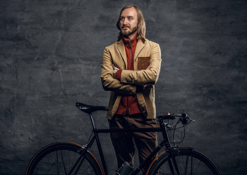 A man posing with single speed bicycle over grey background.