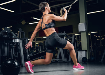 Fototapeta na wymiar Female doing workouts with trx suspension strips in a gym club.