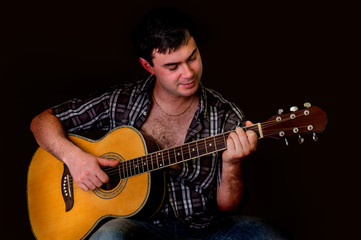 Young man playing acoustic guitar - isolated on black