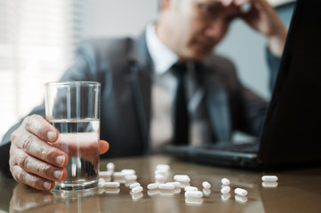Illness, stressed, tired, exhausted, pain from overworked concepts. Asian Businessman holding glass of water with pills. Man has  migraine.