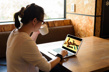 Asian woman use her laptop for working and drinking coffee in coffee shop