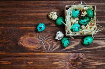 Painted quail eggs in the box over wooden background