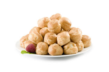 Pile of cream puffs on white plate with raspberry and mint