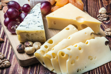 Assorted fresh cheese, fruits and nuts on a wooden table