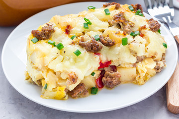 Egg casserole with potatoes, sausage and pepper, on white plate, horizontal