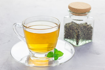 Herbal mint tea in a glass cup with fresh peppermint on background, horizontal