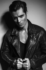 dramatic portrait of a young man pulling his leather jacket