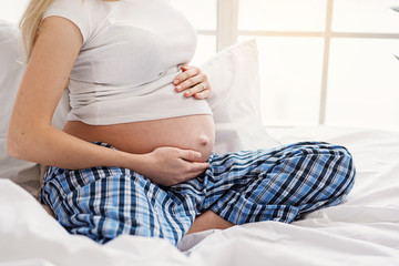 Pregnant woman gently touching her belly by hands