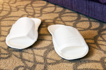 White slippers near the bed in the hotel or at home