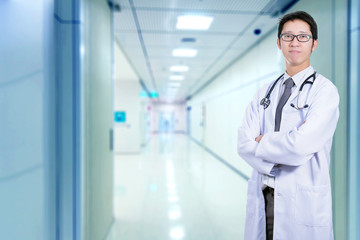 Asian handsome happy doctor hang on stethoscope with blurred surgery operating room in background. Doctor concept.