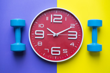 Time for exercising clock and dumbbell with colorful background