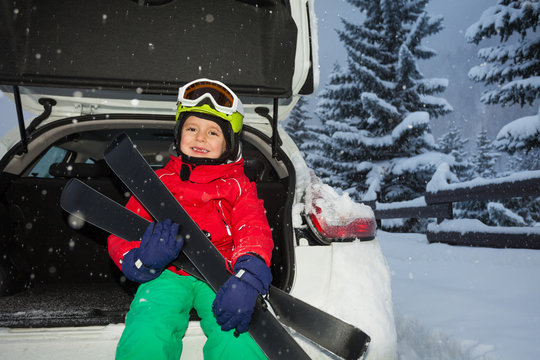 Happy boy sitting in car trunk after ski trip