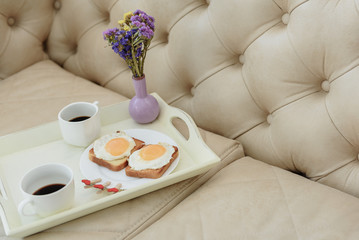 Romantic breakfast with bouquet on couch